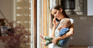 A woman talking on the phone and holding a baby.