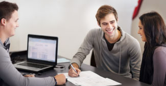 Three people having a meeting and doing paperwork.